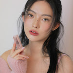 Model holding 3CE Soft Matte Lipstick in Shade Hazy Rose, emphasizing its velvety texture and comfortable matte wear.