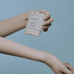 A hand holding the Abib Airy Sunstick over an outstretched arm, showcased against a light blue background, emphasizing its portable design and ease of application.