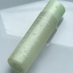 A green bottle of Abib Heartleaf Calming Toner with water droplets, showcasing its calming and hydrating properties.