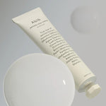 The Abib Jericho Rose Crème tube, showcasing a minimalist design and key ingredients, floating against a soft-focus bubble backdrop, emphasizing hydration and nourishment.