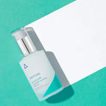 A bottle of Aestura A-Cica 365 Blemish Calming Serum on a vibrant turquoise background, next to a white paper sheet.