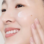 A model gently applying Aestura Atobarrier 365 Cream to the cheek, showcasing a close-up of the ceramide capsules in the texture.