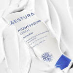 A close-up of the Aestura Atobarrier 365 Cream tube partially submerged in thick white cream, highlighting its moisturizing properties.