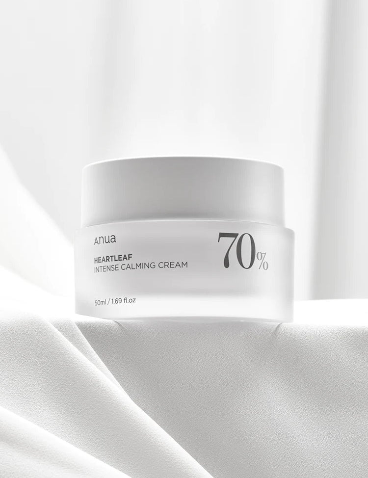A white jar of Anua Heartleaf Intense Calming Cream, labeled with 70% Heartleaf, resting on a soft, textured white surface.