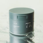 Green jar of Anua Heartleaf 77% Clear Pad floating on water, highlighting its soothing and hydrating skincare benefits.