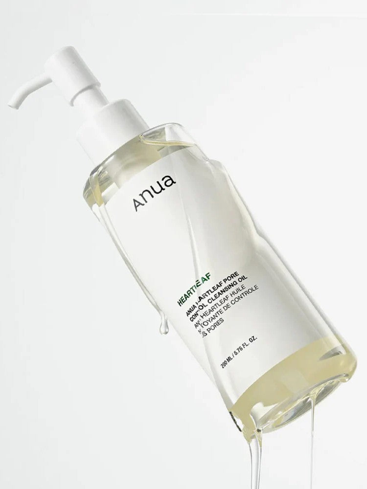 A clear bottle of Anua Heartleaf Pore Control Cleansing Oil with a pump lid, dispensing its oil against a white background.