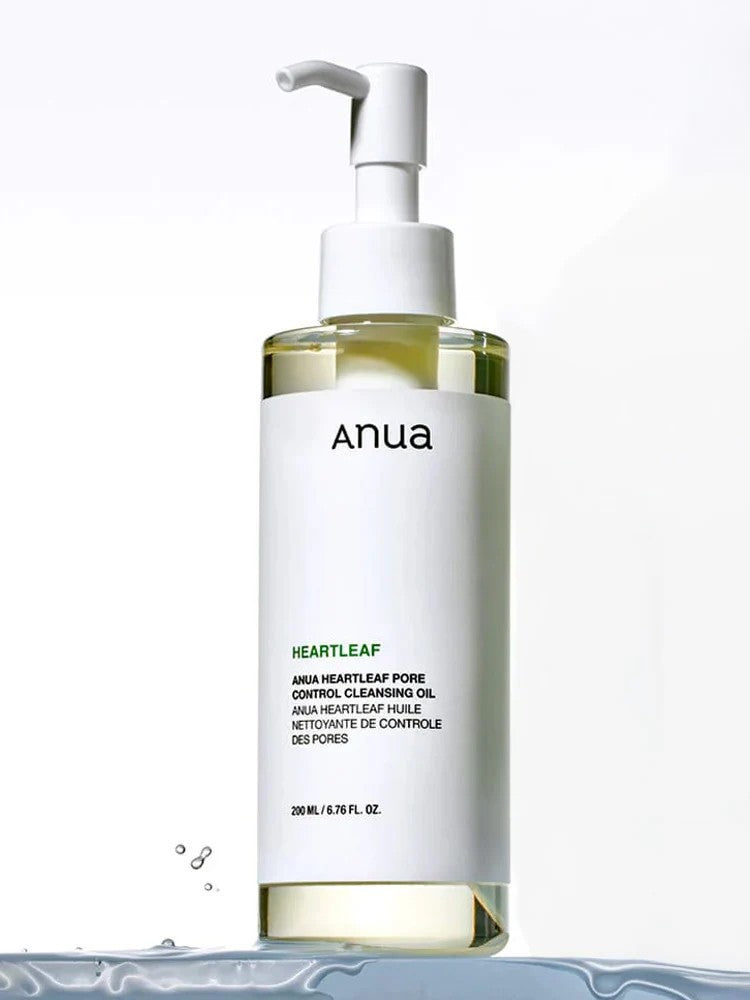 A bottle of Anua Heartleaf Pore Control Cleansing Oil with a pump top and sleek white design, highlighting ingredients on the label, set on a water-like background.