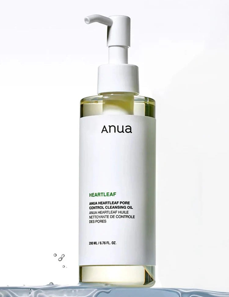 A bottle of Anua Heartleaf Pore Control Cleansing Oil with a pump top and sleek white design, highlighting ingredients on the label, set on a water-like background.