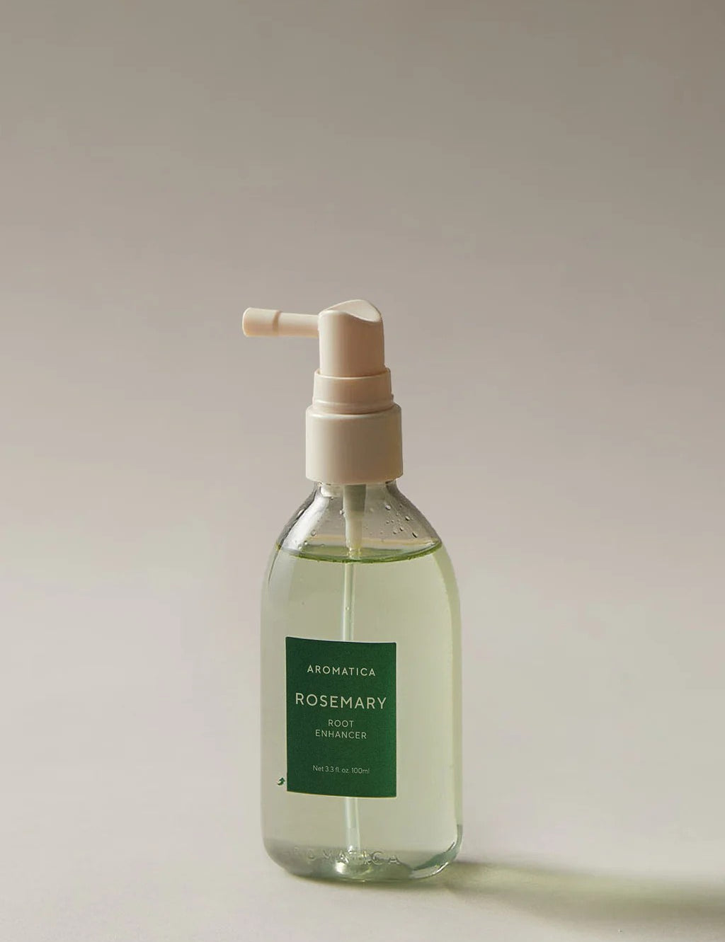 Clear pump bottle of Aromatica Rosemary Root Enhancer hair treatment, shown on a neutral background.