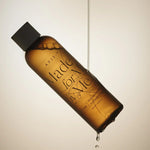 AXIS-Y Biome Comforting Infused Toner, suspended in air with a droplet falling from the bottom against a soft beige backdrop.