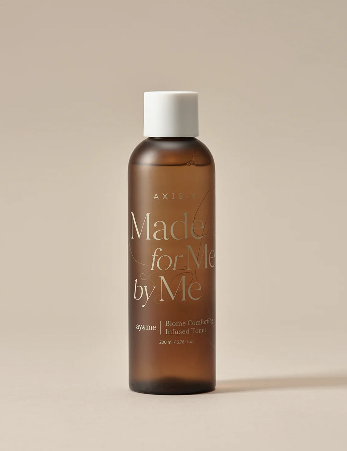 Brown glass bottle of AXIS-Y Biome Comforting Infused Toner labeled 'Made for Me by Me,' set against a neutral background.