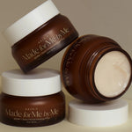 Three brown jars of AXIS-Y 'Made for Me by Me' Biome Ultimate Indulging Cream, elegantly stacked against a beige background.