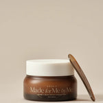 Brown jar of AXIS-Y 'Made for Me by Me' Biome Ultimate Indulging Cream with white lid and brown spatula, set against a beige background.