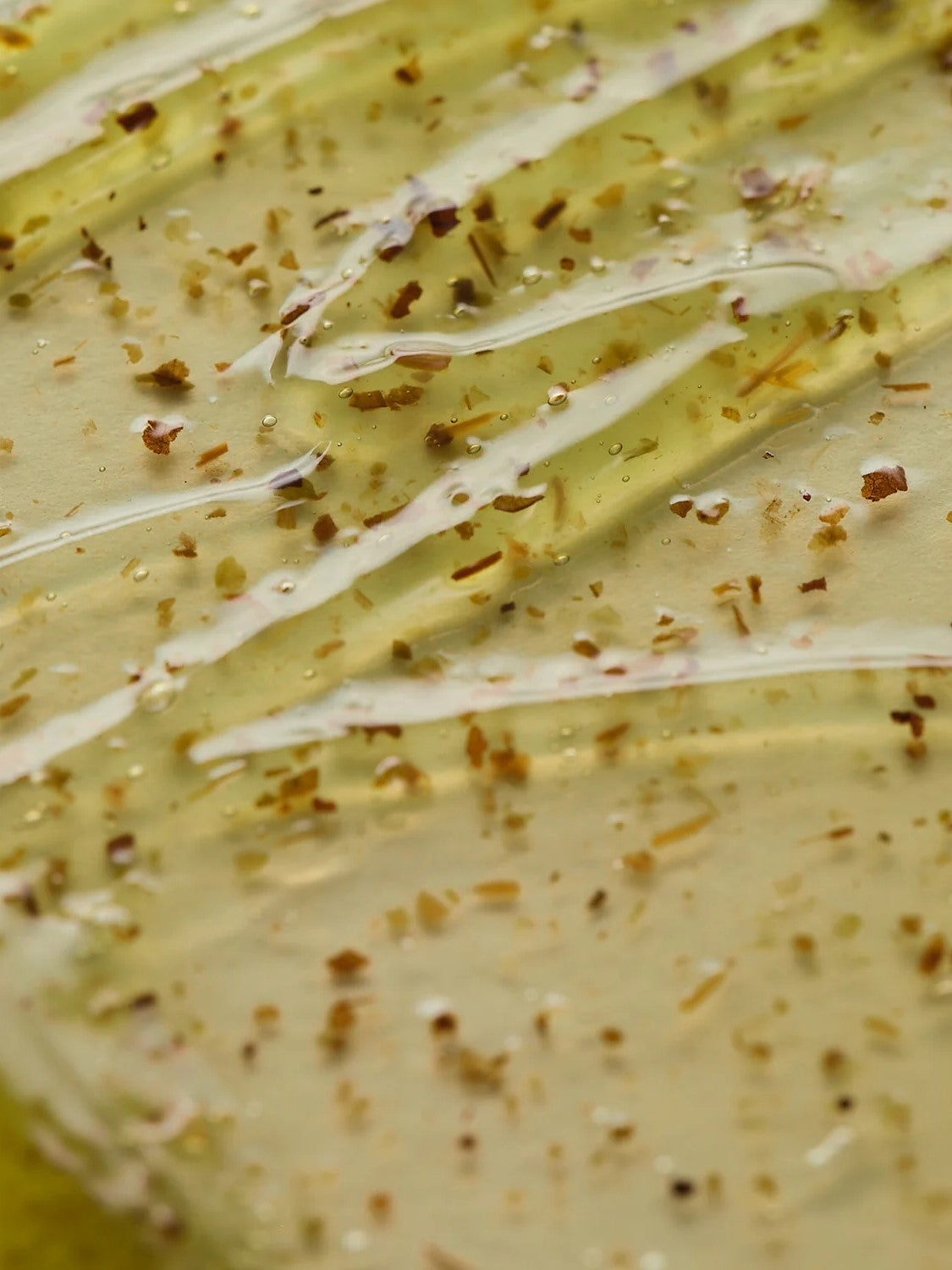 Close-up of glossy, jelly-like texture of AXIS-Y New Skin Resolution Gel Mask with assorted herbs, showcasing key ingredients and reflecting light.