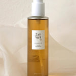 Amber bottle of the Beauty of Joseon Ginseng Cleansing Oil with a white pump top, set against a soft, neutral background, featuring a label with the brand logo in Korean text.