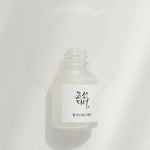 Beauty of Joseon Glow Deep Serum: Rice and Alpha Arbutin with liquid flowing out, showcasing its lightweight texture against a soft white background.