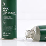 Close-up of Benton Aloe BHA Skin Toner with liquid spilled beside the bottle, showing its light gel-like texture and sleek packaging.