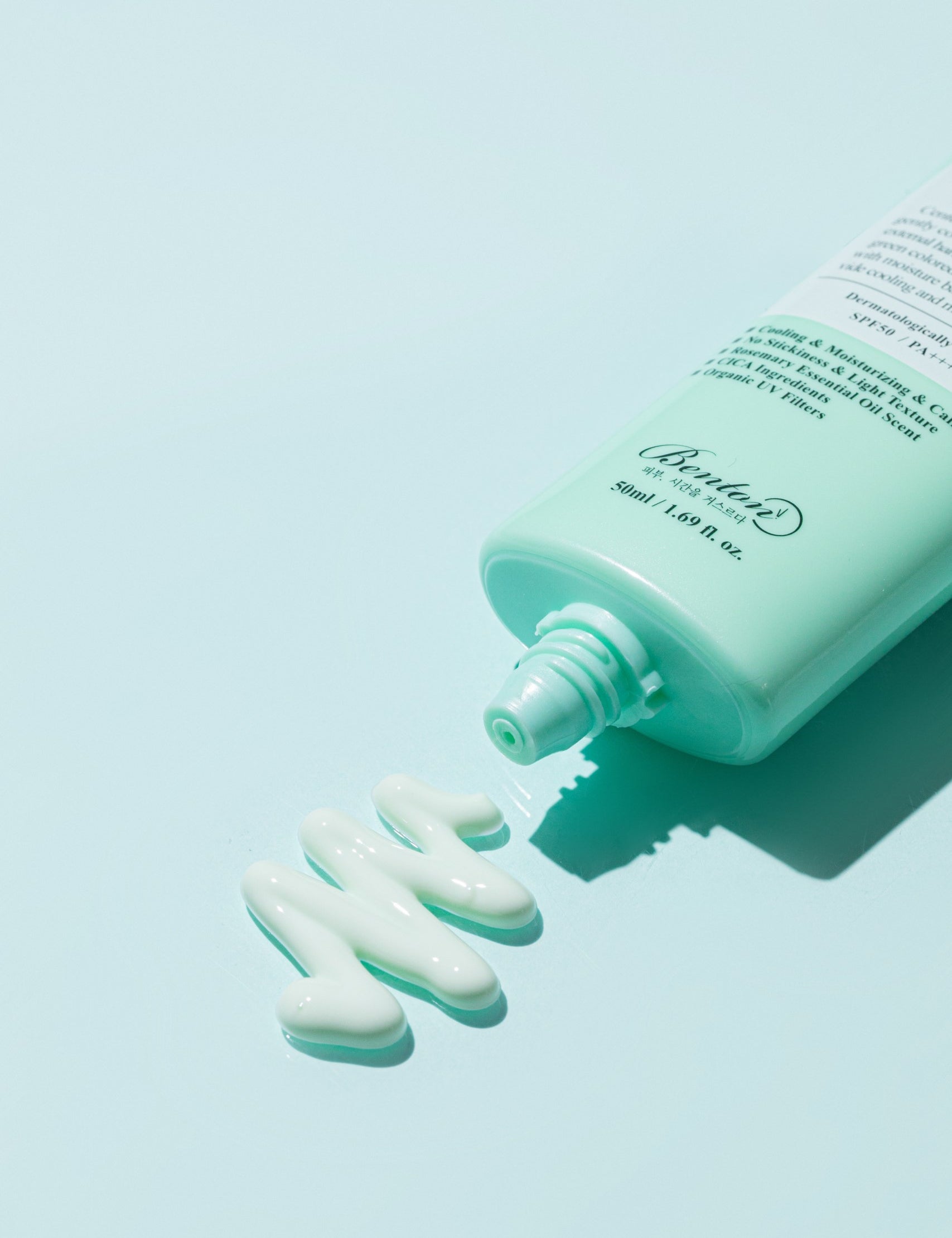 Benton Air Fit UV Defense Sun Cream tube partially squeezed, with a dollop of cream beside it on a pale blue background.