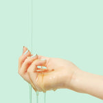 Close-up of Beplain Cicaterol Ampoule’s glossy texture dripping from a hand against a pale mint green background.