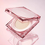 Pink hexagonal compact of CLIO Kill Cover Mesh Glow Cushion, partially open to reveal the cushion inside, on a soft gradient background.