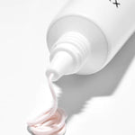 A tube of Cosrx Ultimate Spot Cream with a creamy pink lotion swirl, set against a clean white background.