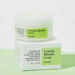 A jar of Cosrx Centella Blemish Cream with a white lid and green label, resting on its packaging against a white and green backdrop. 