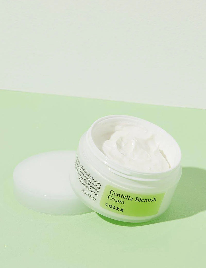 Opened jar of Cosrx Centella Blemish Cream, highlighting its smooth, creamy texture, set against a pastel green background for soothing skincare.