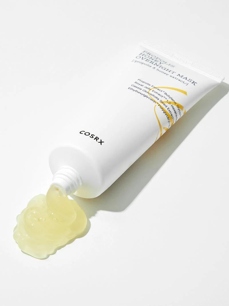 A tube of Cosrx Propolis Honey Overnight Mask with yellow gel spilling from the tip, highlighting its texture against a white background.