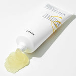 A tube of Cosrx Propolis Honey Overnight Mask with yellow gel spilling from the tip, highlighting its texture against a white background.