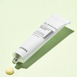 A tube of Cosrx Retinol 0.1 Cream with a small dollop of cream texture next to it, set against a pale green background.