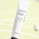 A tube of Cosrx Retinol 0.1 Cream on a soft yellow background, with Vitamin E and Panthenol highlighted on its label to promote youthful-looking skin.