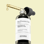 Cosrx The Vitamin C 23 Serum with dropper showcasing its texture, with visible text describing skin health benefits, set against a light yellow background.