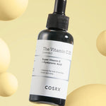 Black dropper bottle of Cosrx The Vitamin C 23 Serum against a soft yellow background, highlighting its skin benefits.
