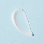 A smooth, glistening white cream droplet on a soft blue background, showcasing the texture of Cosrx Ultimate Nourishing Rice Overnight Spa Mask.
