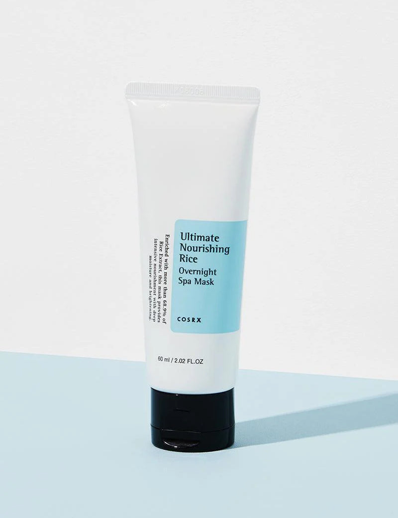 Cosrx Ultimate Nourishing Rice Overnight Spa Mask in a white tube with blue label, resting on a light blue background.