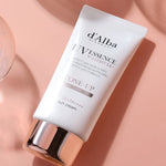 A tube of d'Alba UV Essence Waterfull Sun Cream on a pink surface, highlighting its tone-up and moisturizing formula for radiant, hydrated skin.