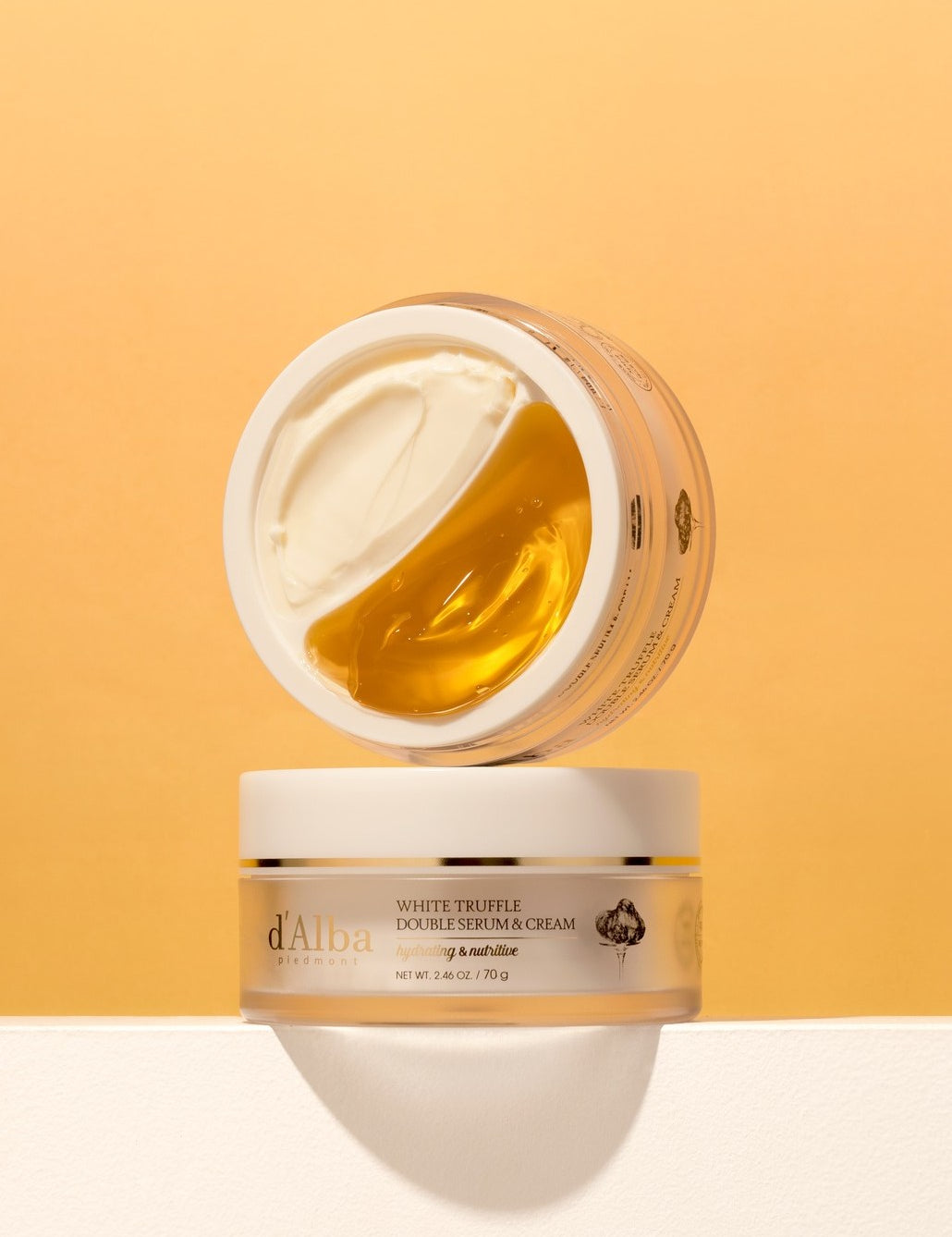 Two jars of d'Alba's White Truffle Double Serum and Cream on a soft orange background, showcasing creamy and golden texture.