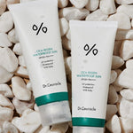 Two tubes of Dr. Ceuracle CICA Regen Waterproof Sun Cream with SPF 50+ PA++++, surrounded by white pebbles and water droplets, highlighting its waterproof formula and suitability for babies as indicated on the labels.