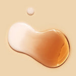 Two droplets of liquid, one creamy white and one amber, rest on a smooth beige surface, showcasing the cream-essence texture of Dr.Ceuracle Vegan Kombucha Tea Essence.