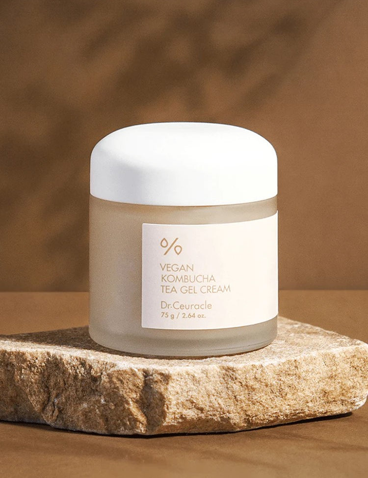 A jar of Dr. Ceuracle Vegan Kombucha Tea Gel Cream on a stone surface, with a warm, blurred background highlighting its lightweight and hydrating formula.