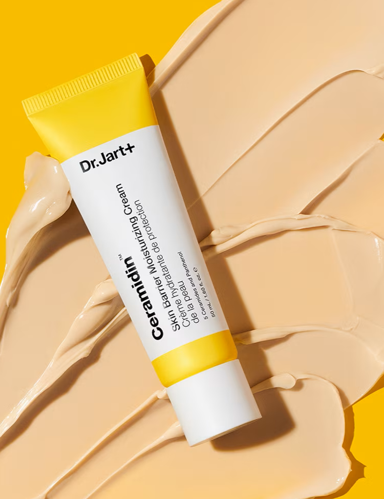 A tube of Dr. Jart+ Ceramidin Skin Barrier Moisturizing Cream resting on a beige smear of its texture against a bright yellow background.