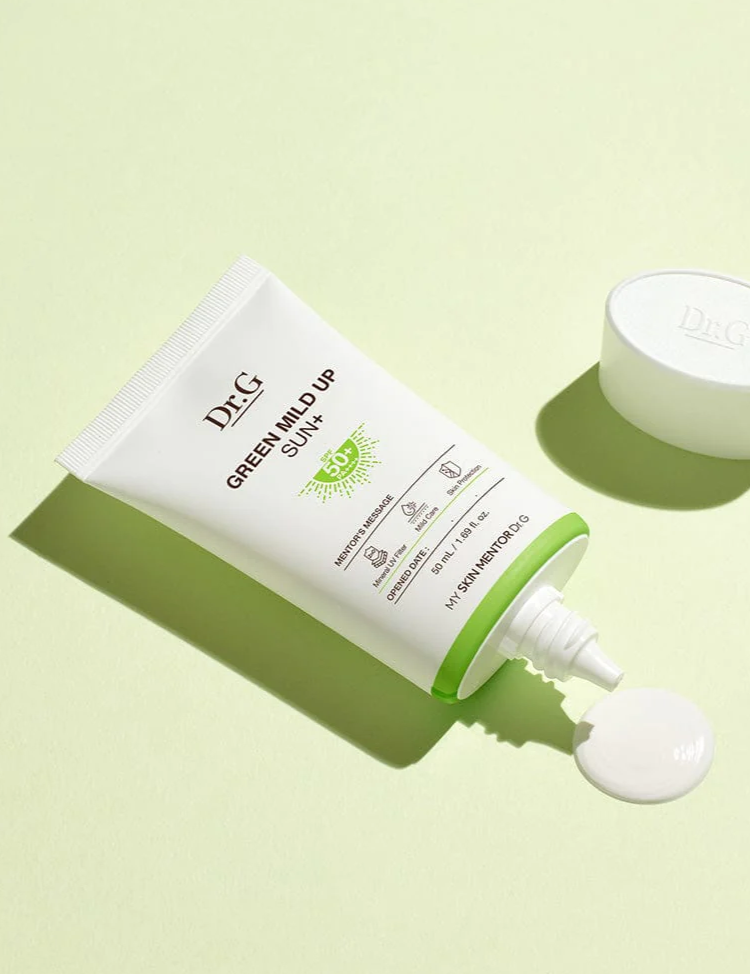 Dr.G Green Mild Up Sun+ Sunscreen tube dispensing a dollop of cream onto a light green background, highlighting its creamy yet lightweight texture.