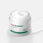 Open jar of Dr.G Red Blemish Cica Soothing Cream with smooth white cream texture spilling beside it, highlighting its lightweight yet nourishing formula.