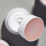 An open jar of Etude Moistfull Collagen Deep Cream, showcasing its creamy white texture and soft pink lid, set against a muted gray background.
