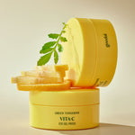 Stacked jars of Goodal Green Tangerine Vita C Eye Gel Patch, surrounded by fresh lemon slices and a green leaf, emphasizing a vibrant and refreshing skincare concept.