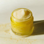 A jar of Goodal Vita-C Dark Spot Care Cream in yellow, showing its creamy texture with visible tangerine pieces, set against a light background.