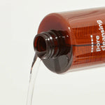 Hanskin Pore Cleansing Oil dispensing clear liquid against a neutral background, highlighting its lightweight texture.