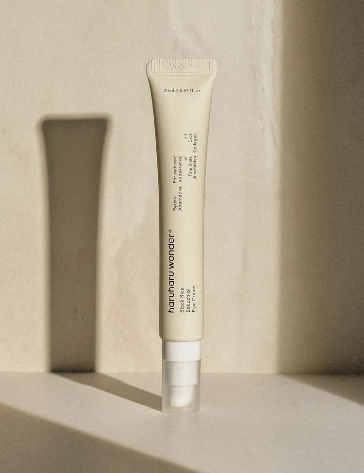 A sleek tube of Haruharu Wonder Black Rice Bakuchiol Eye Cream standing on a softly lit surface against a minimalist background.