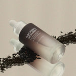 Haruharu Wonder Black Rice Hyaluronic Botanical 2GF Wonderful Ampoule surrounded by black rice grains on a soft beige background.