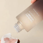 A hand holding Haruharu Wonder Black Rice Hyaluronic Toner, pouring onto a cotton pad, highlighting its lightweight texture.